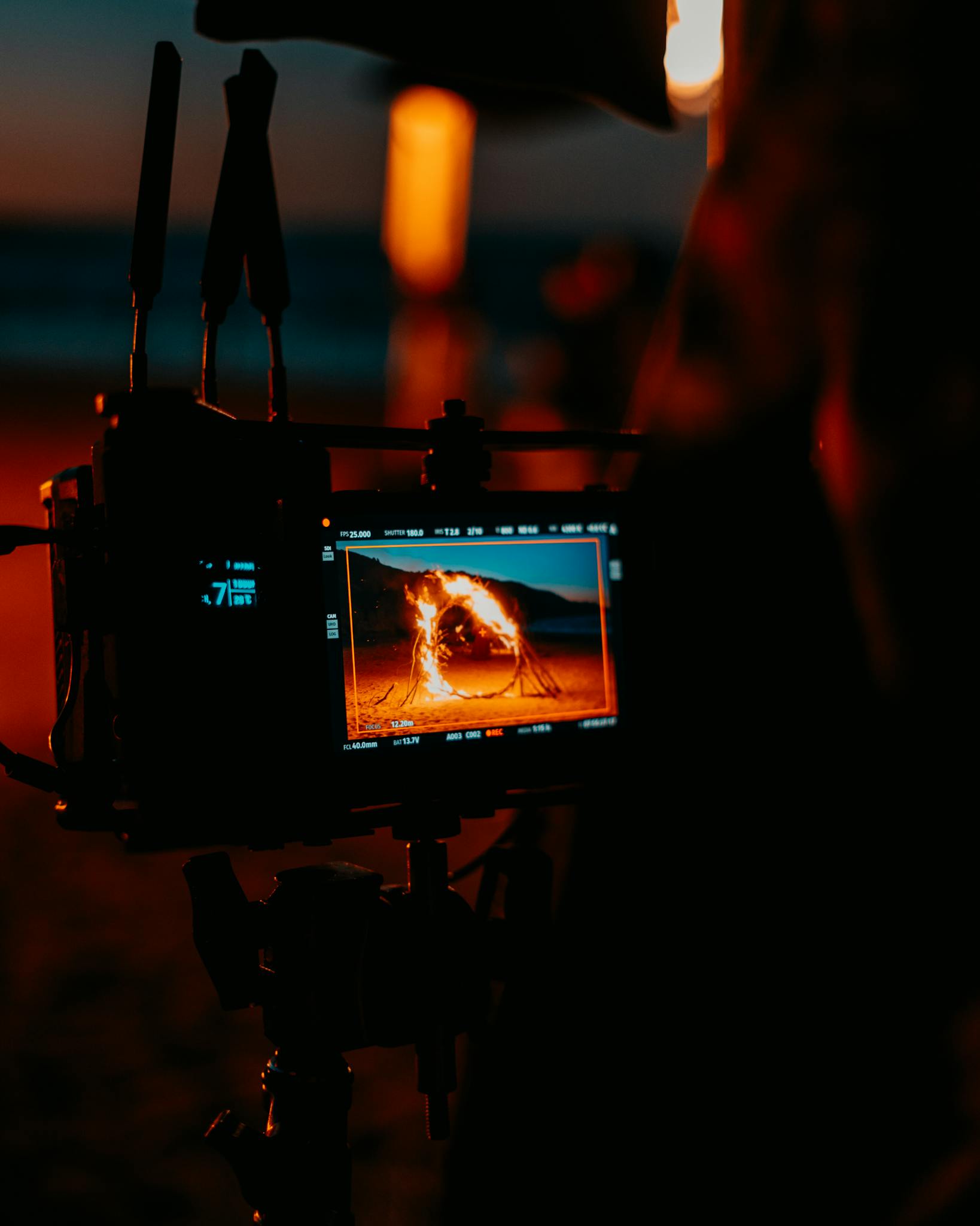 Capture of a cinematic scene being filmed at a beach during dusk, showing fire display.
